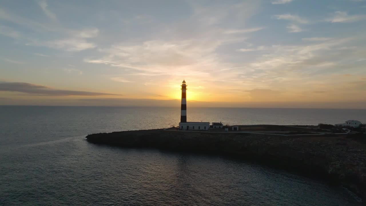 金色的阳光照耀在阿图克斯灯塔梅诺卡岛地标海滩海岸无人机空中沿海小岛，平静的海水在巴利阿里群岛视频素材