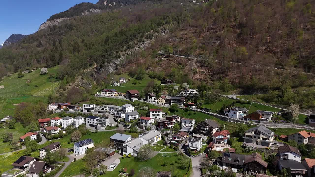 瑞士小镇特里米斯郊区的航拍近景。在春天的树林间，通往山顶的山路。瑞士公寓酒店在城市。视频素材