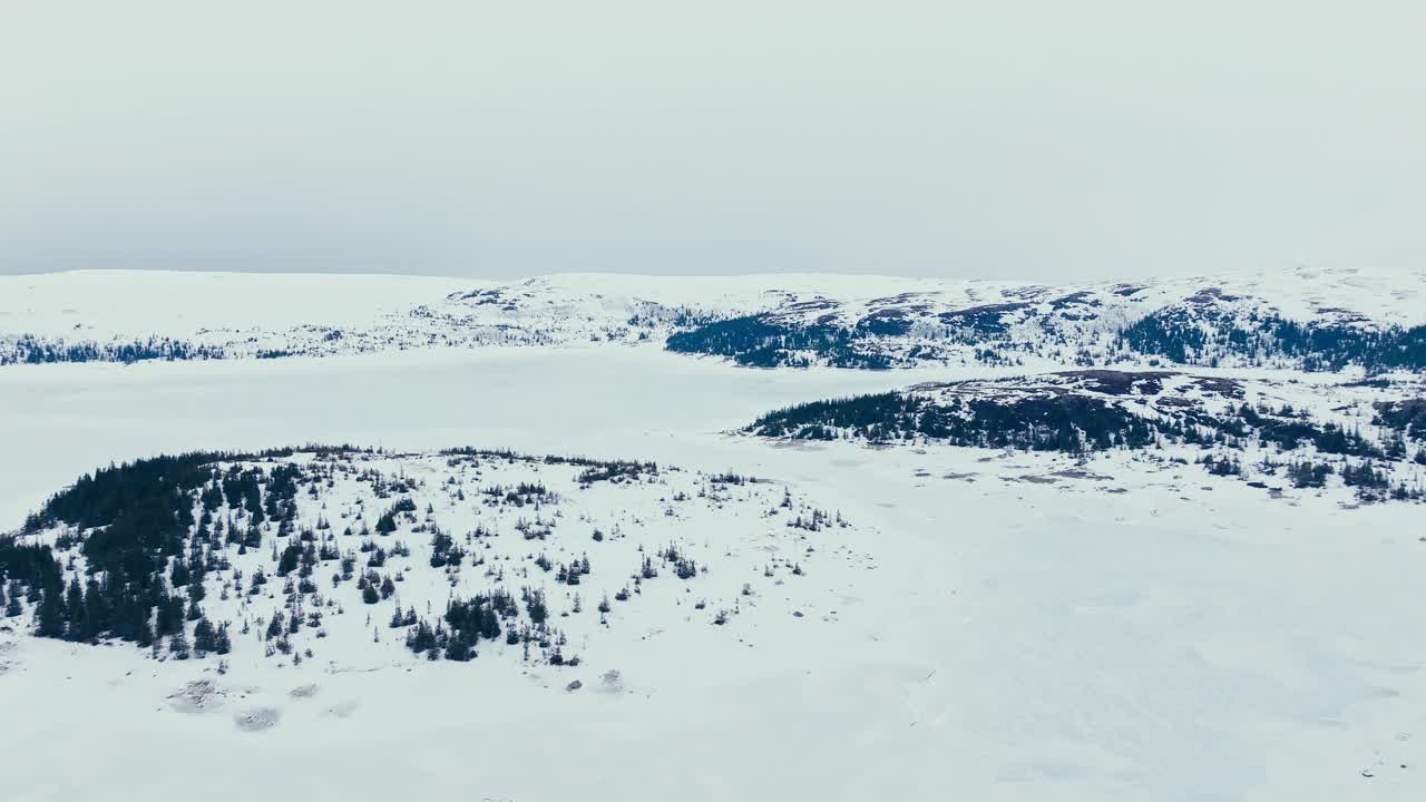 挪威因德福森冬季的雪山山腰景观和森林树木。空中拍摄视频素材