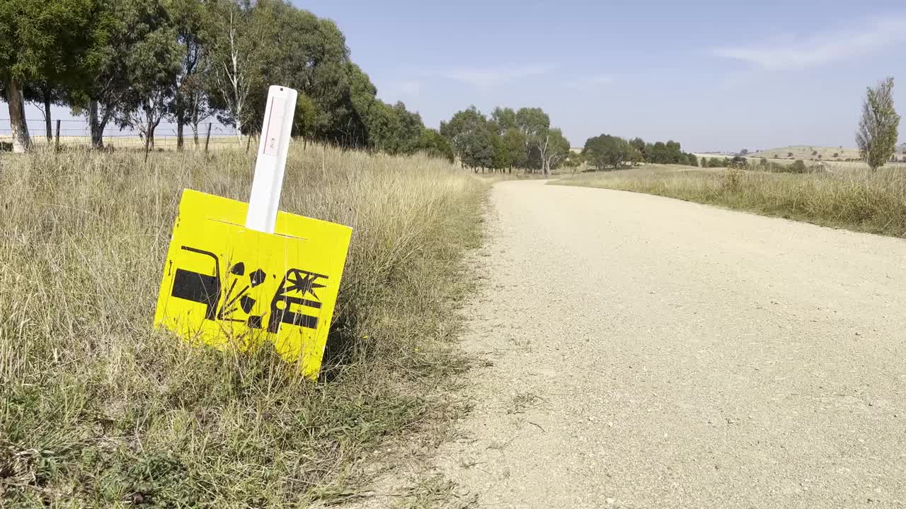 在新南威尔士州地区的一条堤道前，一条干燥而尘土飞扬的道路上竖立着一个松散的砾石警告标志视频素材