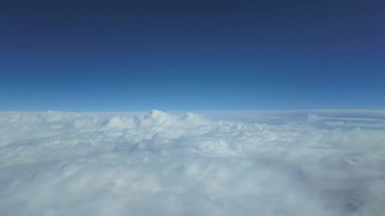 鸟瞰图飞行员POV飞越动荡的天空与一些湍流，与深蓝色的天空。4 k Hyperlapse。视频素材