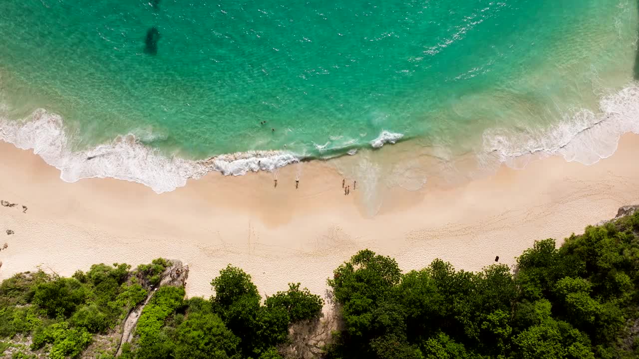 夏天，人们在印尼巴厘岛努沙佩尼达岛清澈的海水中游泳。-航拍视频素材