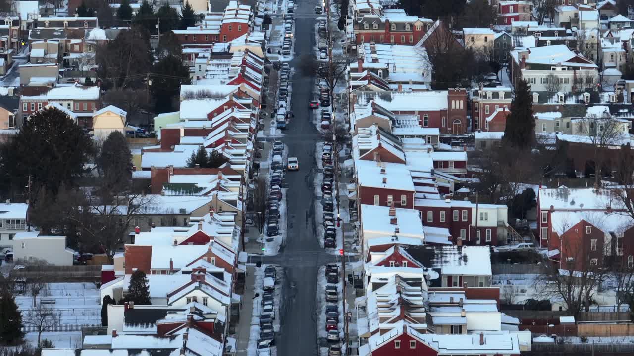 美国小镇的冬日景象，大街上停着汽车。小镇上房子的雪屋顶。航拍变焦广角镜头。建立无人机射击。视频素材