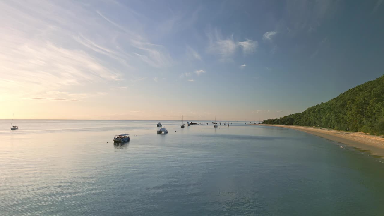 日落天际线，船只漂浮静止，无人机低飞自然海滩莫顿岛，澳大利亚海上旅游目的地视频素材