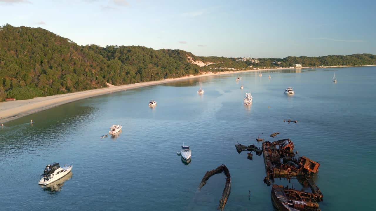 船只仍然漂浮在沉船周围，在坦加卢马莫尔顿岛森林丘陵景观，无人机缓慢飞行视频素材