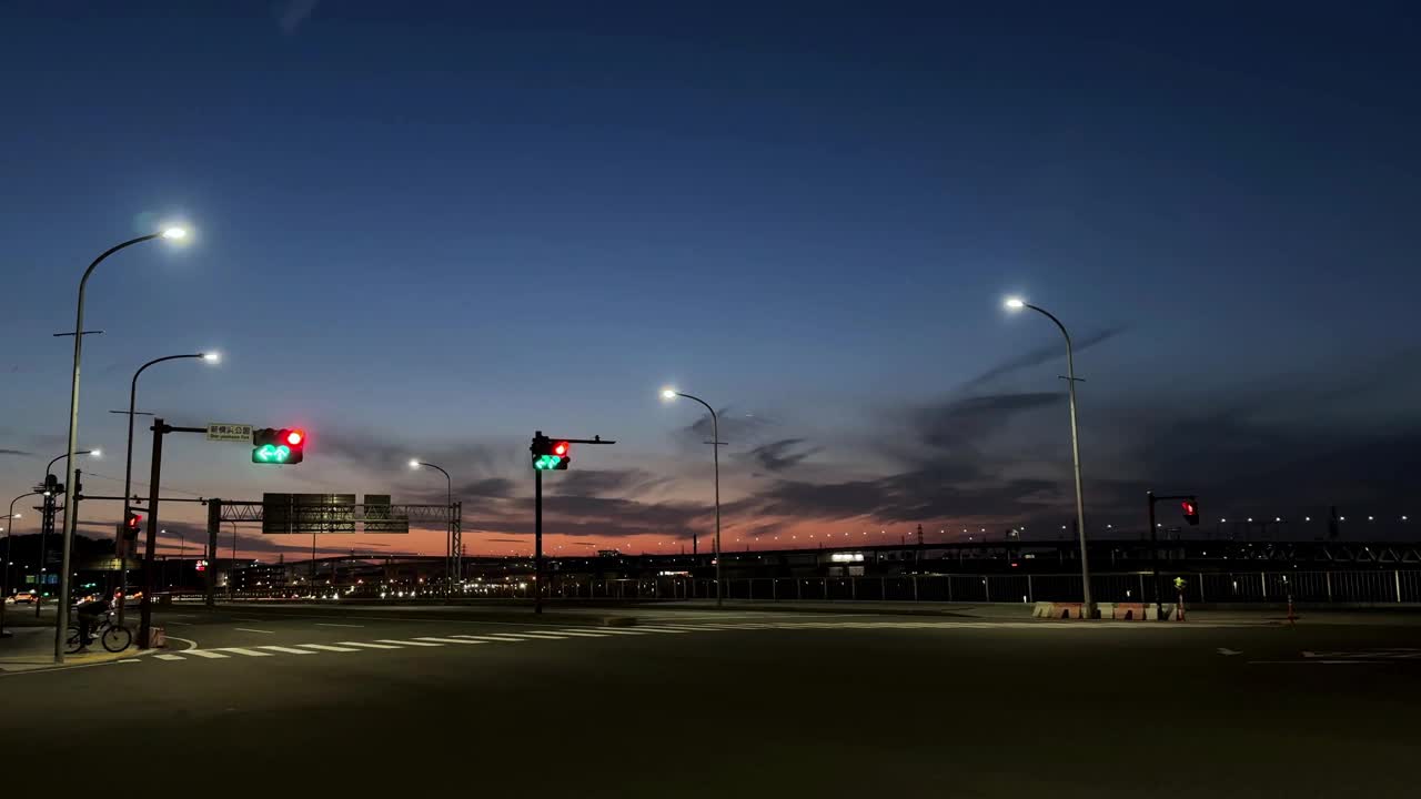 黄昏的城市景观，交通信号灯和空旷的道路，背景是充满活力的日落天空视频素材