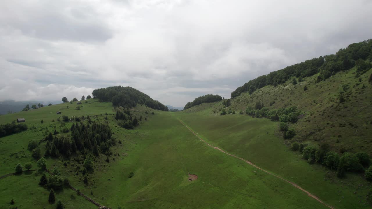 郁郁葱葱的青山在多云的天空下，鸟瞰一片宁静的景色视频素材