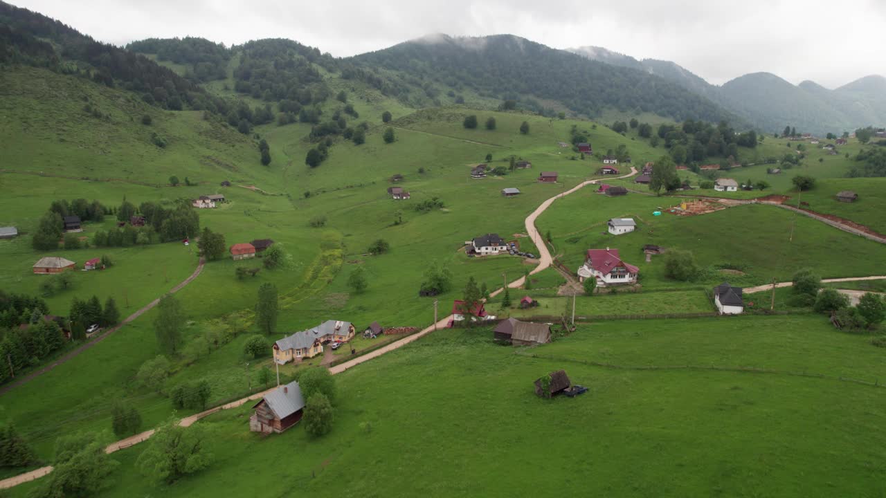 在罗马尼亚的Sirnea村，在阴天鸟瞰图，散布着房屋和郁郁葱葱的青山视频素材