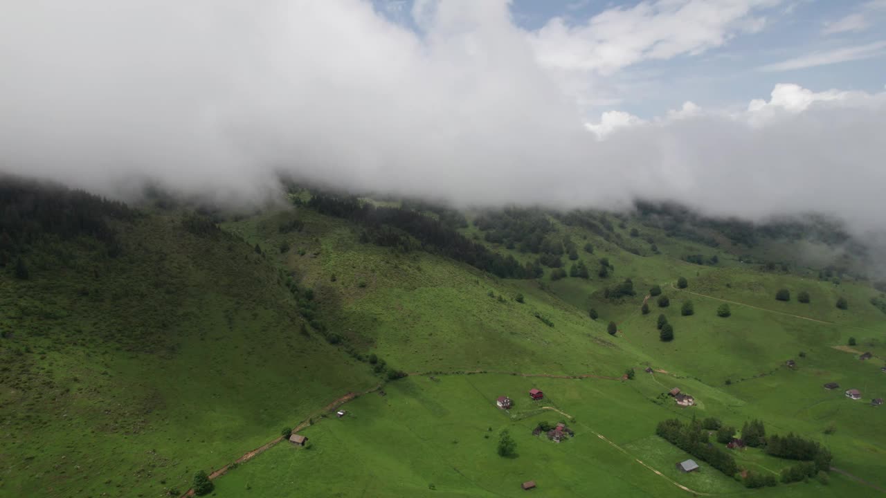 鸟瞰图:郁郁葱葱的绿色山谷，低低的云层，森林覆盖的山丘和零散的农村住宅视频素材