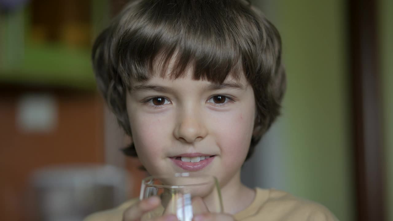 男孩从杯子里喝干净的水。小男孩在家里喝玻璃新鲜透明纯过滤矿泉水。特写孩子喝杯水健康的身体护理。健康的生活方式。视频素材