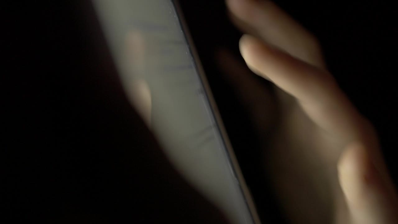 女孩在晚上用手指浏览数码平板电脑。使用智能手机，浏览社交网络的人。近距离手指滚动社交媒体应用程序或阅读新闻动态在线。视频素材