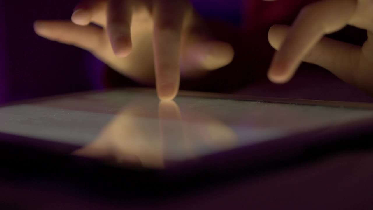 女孩晚上在触摸屏数码平板电脑上打字。在移动电脑上输入文章、文本或文件的人的手近距离。人的手打字文本信息电子邮件在平板电脑触摸屏键盘。视频素材