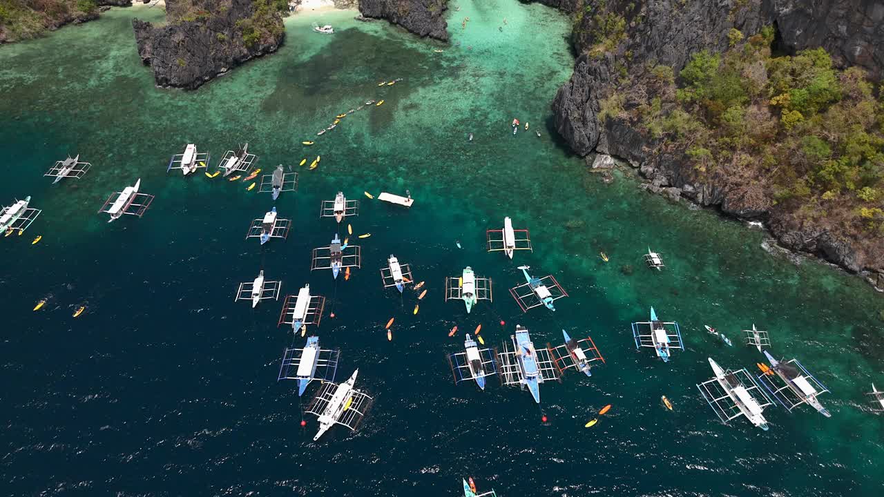 低空飞行，飞越田园诗般的蓝色泻湖入口，进入泻湖本身，游客在下面的水中划着五颜六色的皮划艇。视频素材