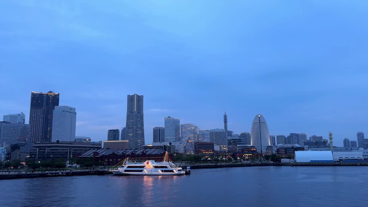 黄昏的城市景观，灯火通明的建筑和河上的船，宁静的城市景观视频素材