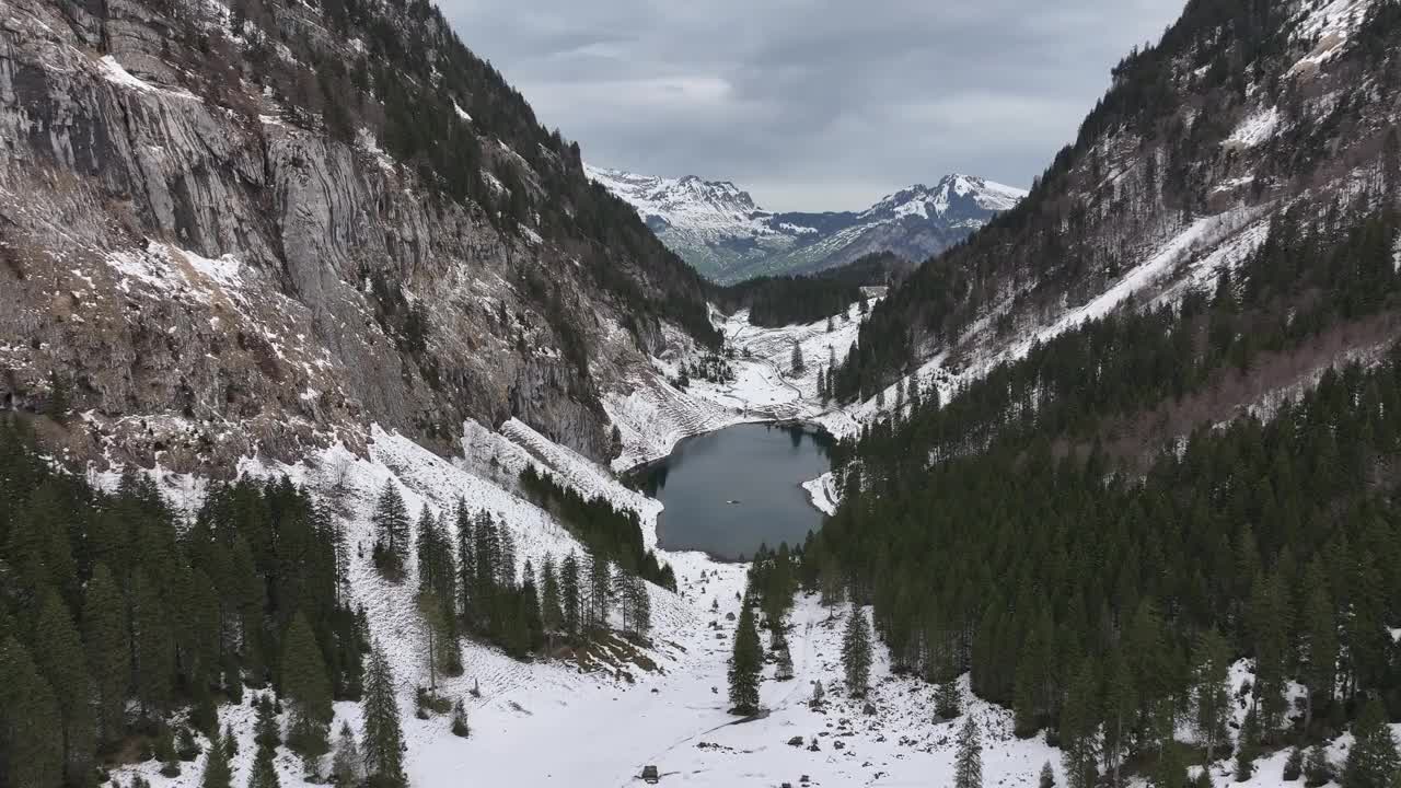 俯瞰瑞士格拉鲁斯北部菲尔兹巴赫的塔哈尔普湖，周围是白雪覆盖的森林和崎岖的山脉视频素材