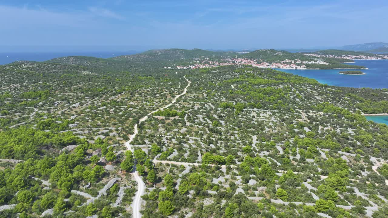 航拍:空旷的柏油路穿过风景，通向一个海滨小镇。视频素材