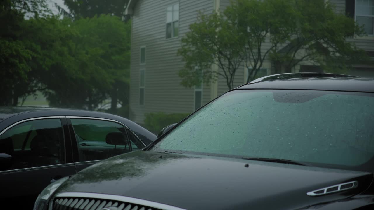 大雨暴雨。雨点落在郊区房子附近的停车场上。视频素材