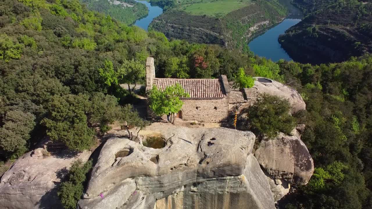 俯瞰巴塞罗那蜿蜒河流的岩石山上一座古老的石头教堂，鸟瞰图视频素材