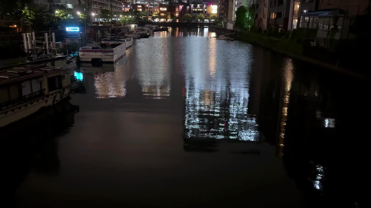 夜晚的城市运河，灯火通明的建筑物和船只倒映在水面上视频素材