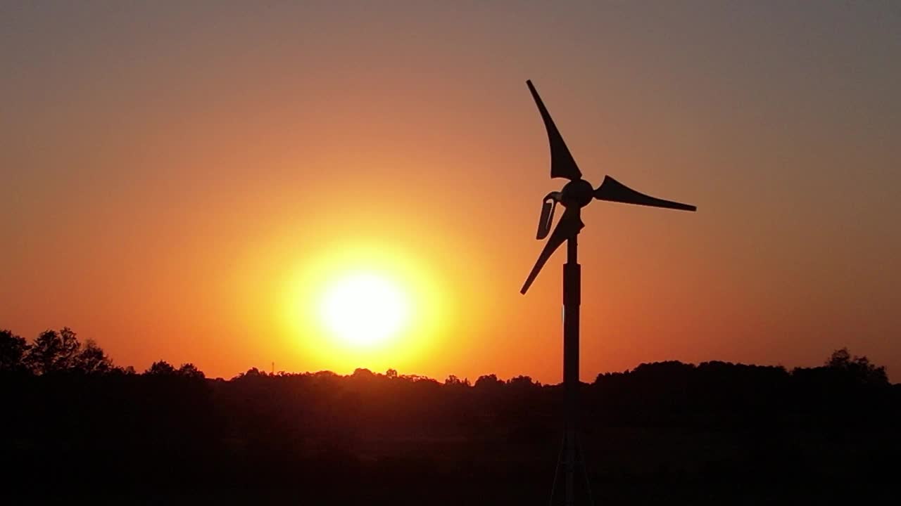 夕阳背景下，风力逐渐减弱，风力发电机叶片缓慢旋转——可再生能源发电的终结视频素材