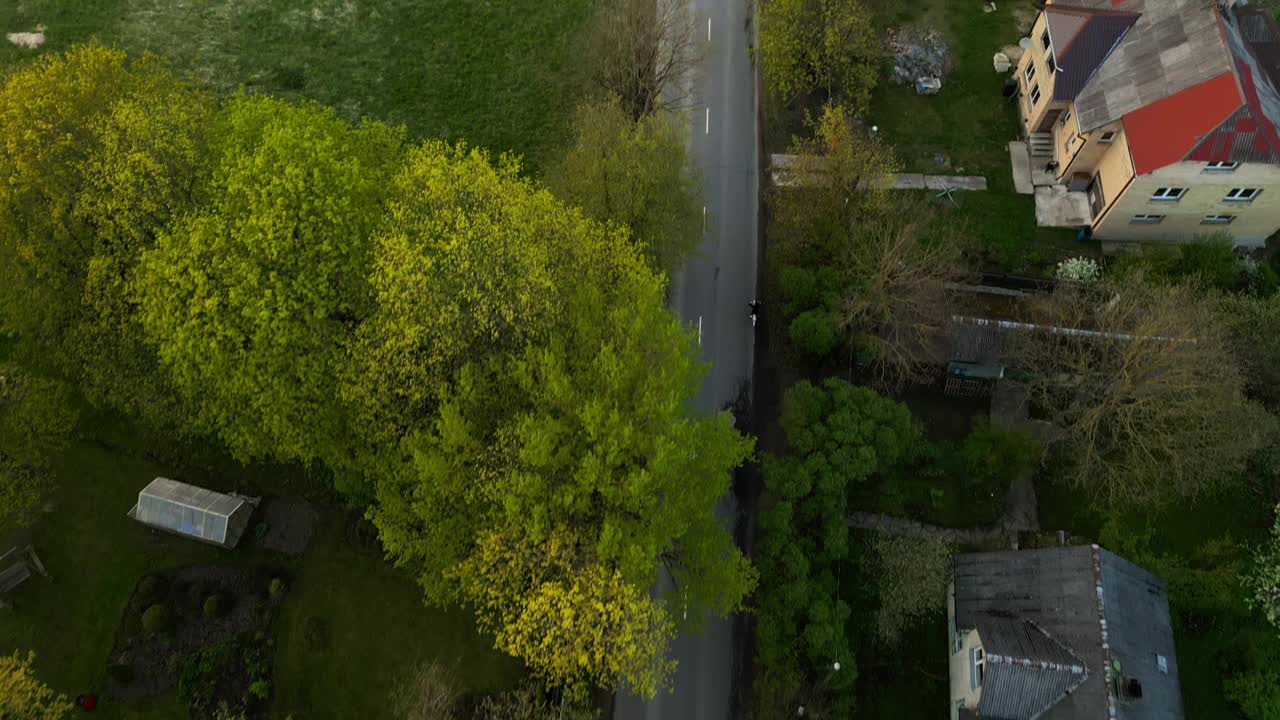 鸟瞰乡村公路，骑自行车的人在绿树丛中，这是一段运动与宁静的和平之旅视频素材