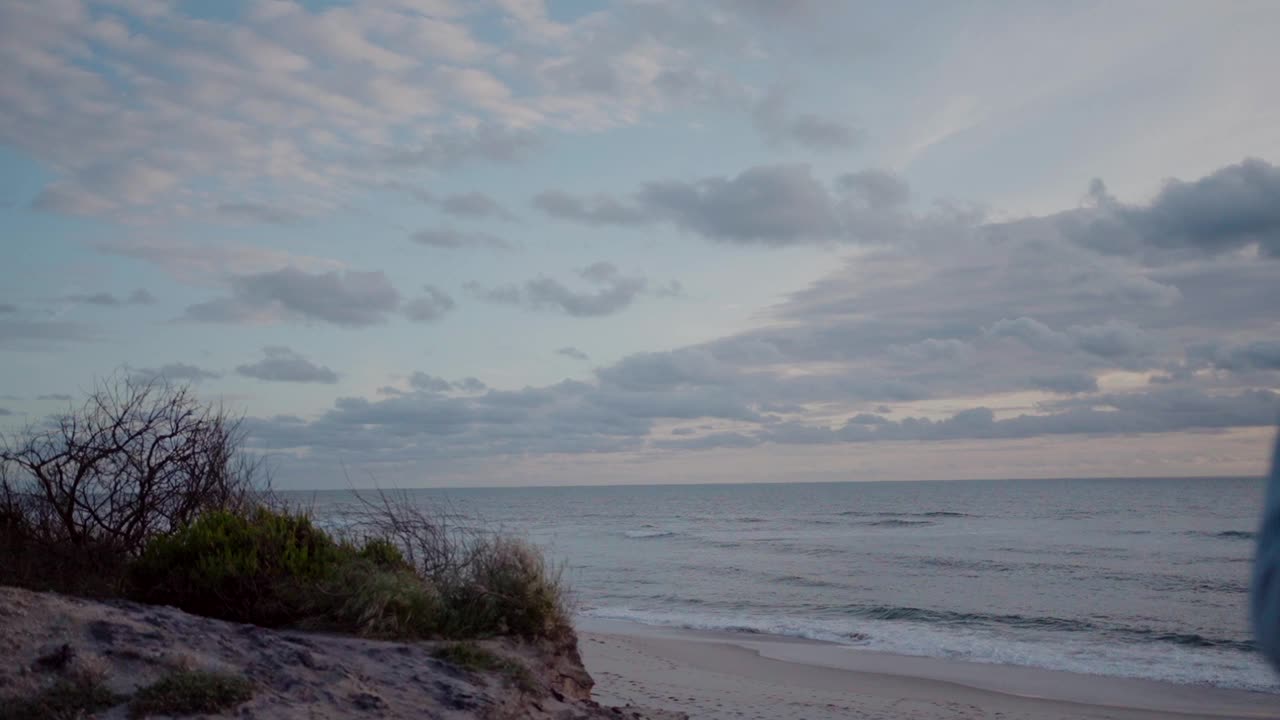 日落景色在奥瓦尔海滩与平静的海浪和多云的天空在葡萄牙。视频素材