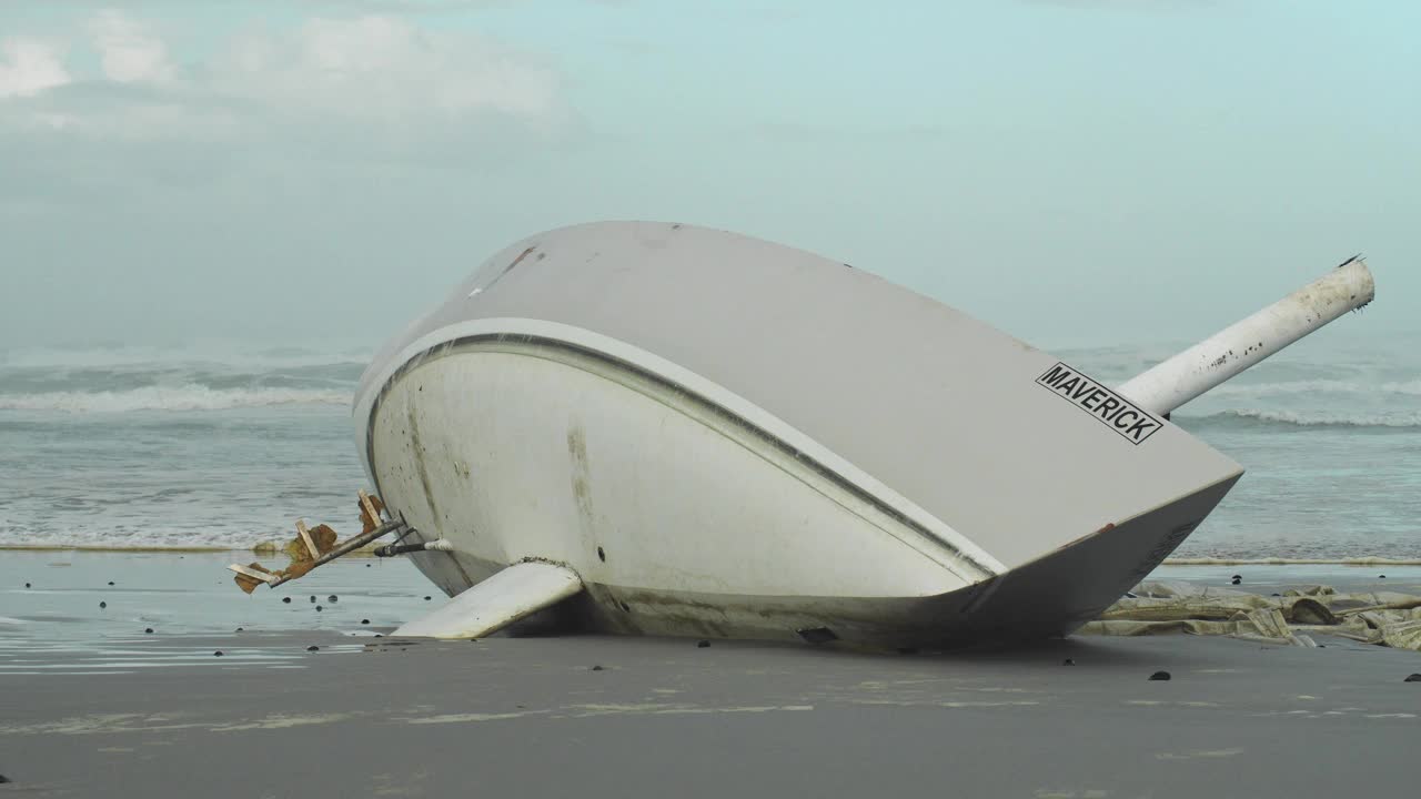 海浪冲过去被冲上岸的游艇在阴暗的海滩-船体的镜头视频素材