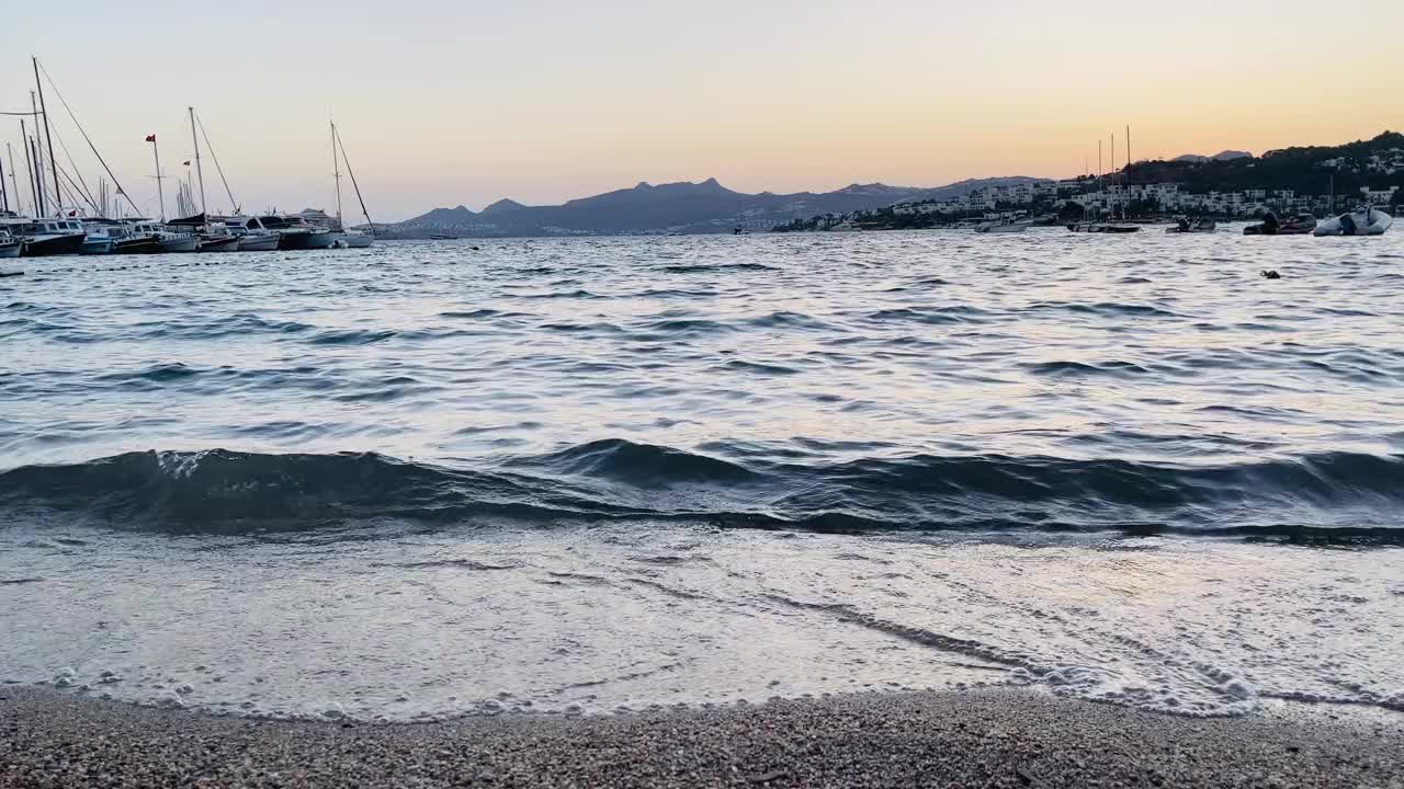 黄昏时，柔和的海浪冲刷着鹅卵石沙滩，夏日出游视频下载