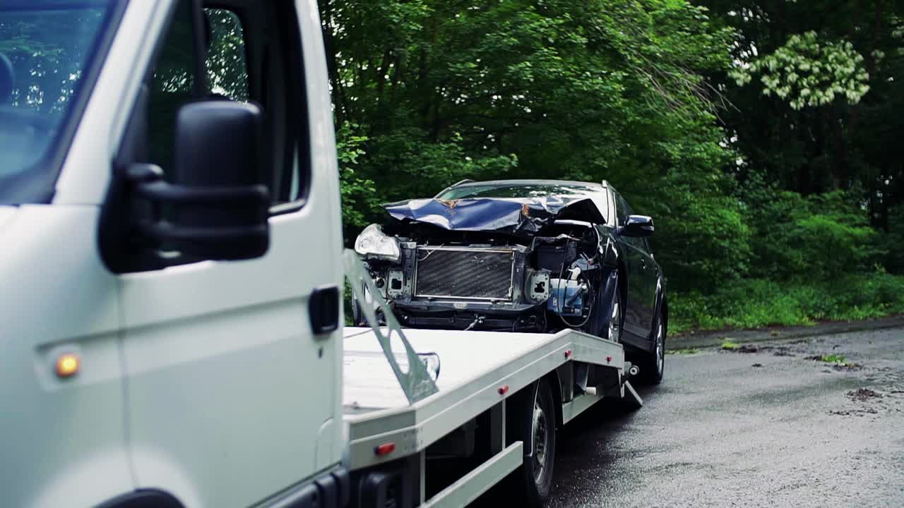 事故发生后，一辆撞车的汽车被拖上了拖车。视频素材