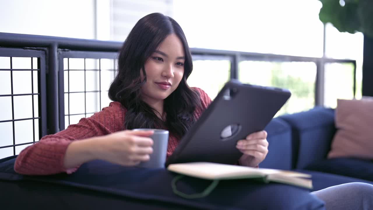 一个亚洲女人一边喝咖啡一边看书。视频素材