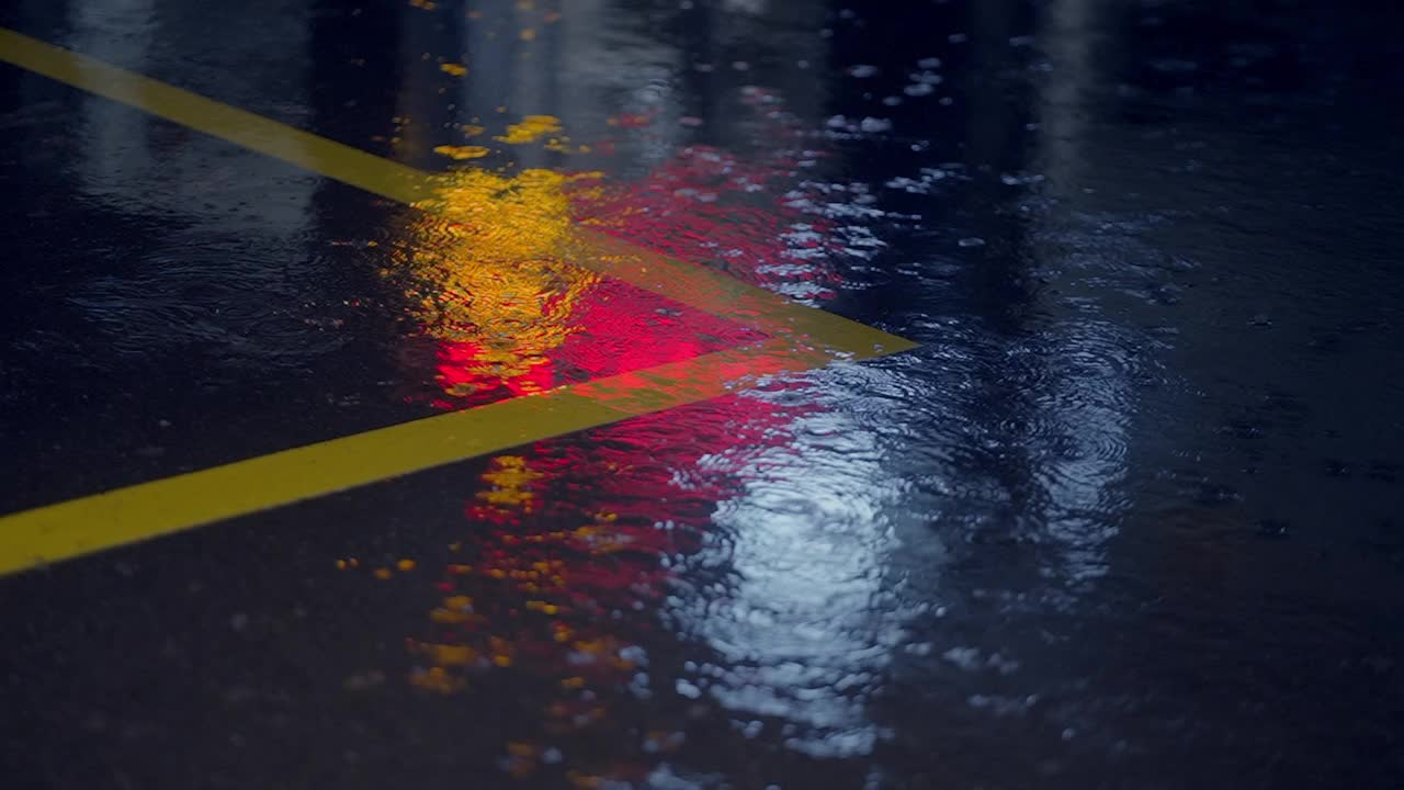 雨夜的城市街道，潮湿的路面反射出交通信号和黄线视频素材