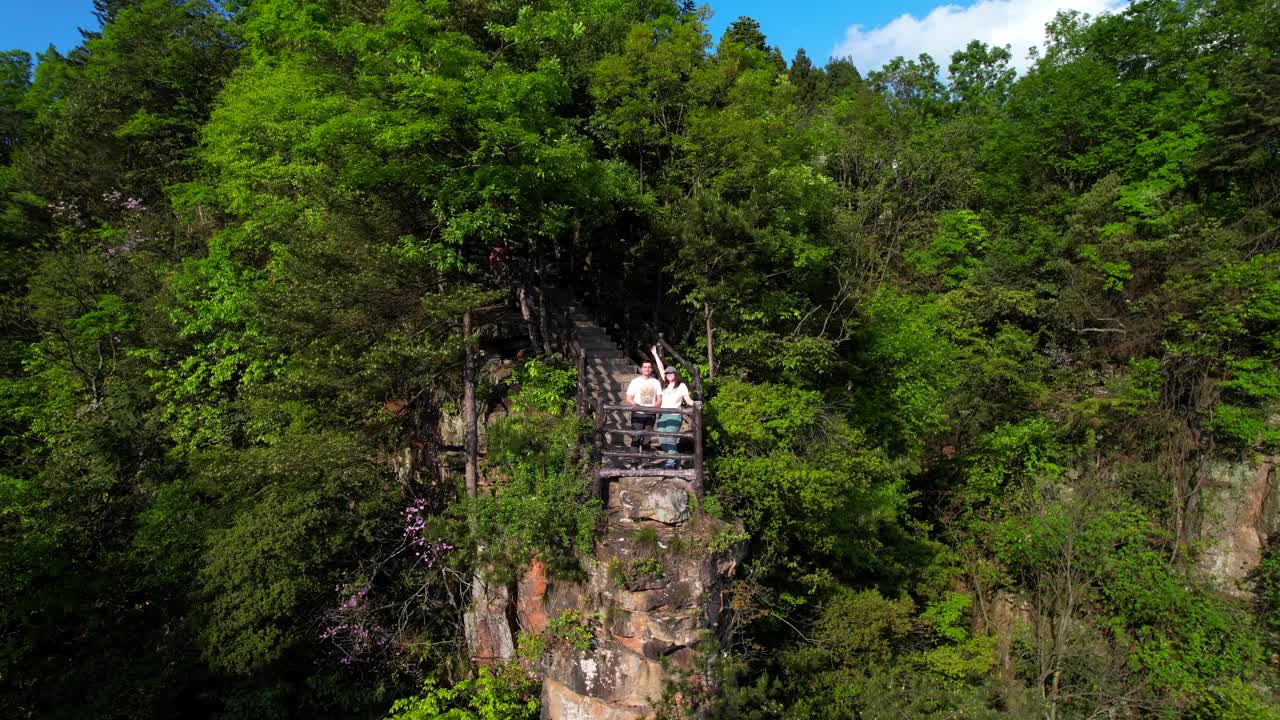 一对夫妇在天子山郁郁葱葱的绿色景观和高耸的岩层中观景。张家界,中国。空中视频素材