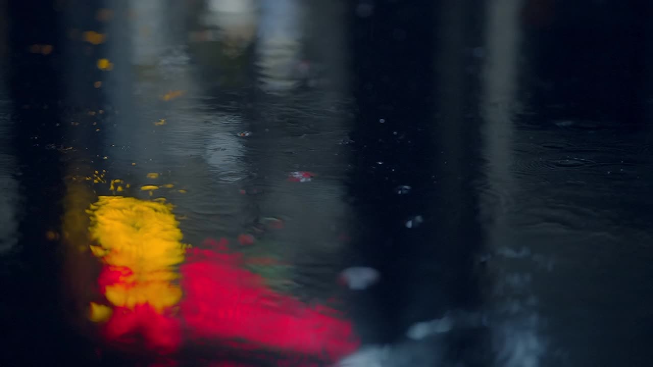 雨夜，城市灯光映照在雨水覆盖的水面上，形成迷人的城市景象视频素材