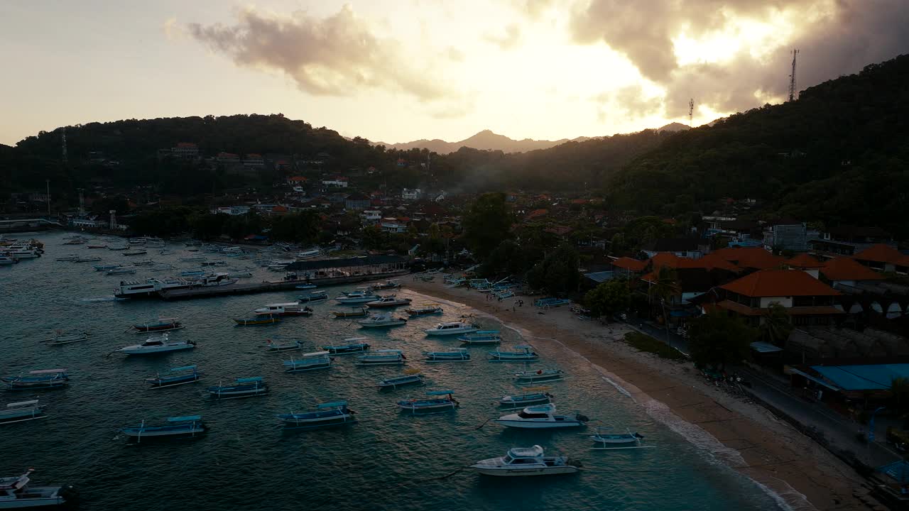 日落时分，船只停泊在印尼巴厘岛的Pantai Padang Bai。空中侧视频素材