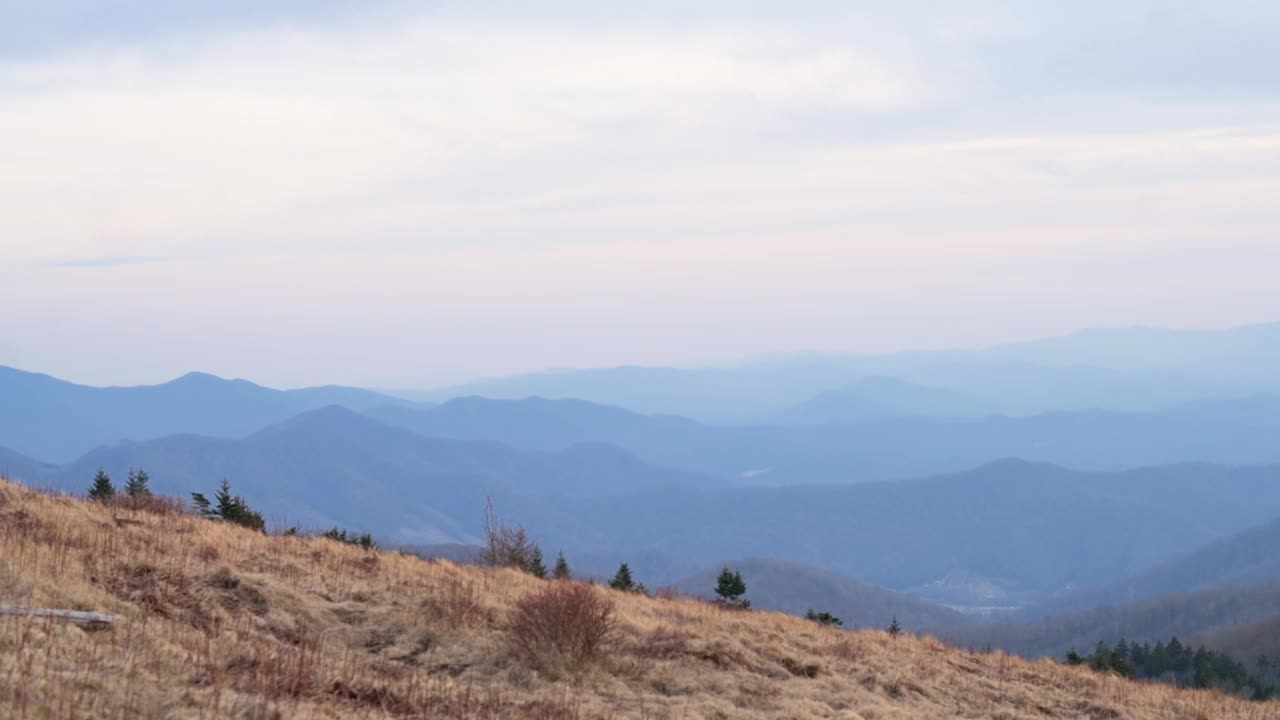 黄昏时的宁静山景，在多云的天空下，层层叠叠的山脉逐渐消失在远处，捕捉到大自然的宁静和美丽。视频素材