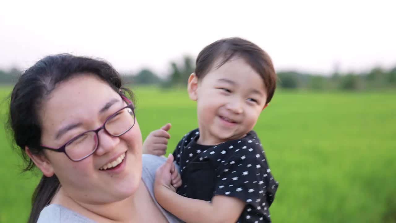 亚洲可爱男孩和妈妈在田野里玩花。全家在公园度假。课堂外教育概念。视频素材