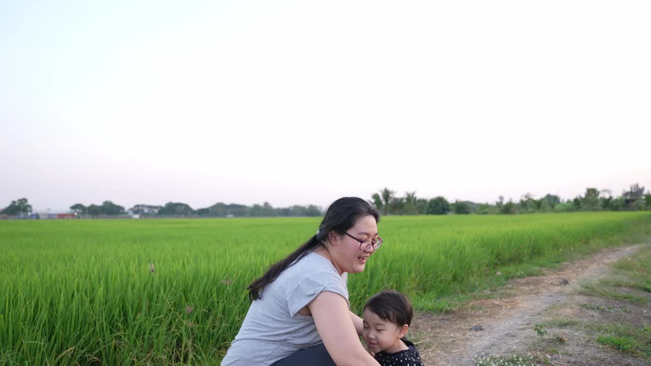 亚洲可爱男孩和妈妈在田野里玩花。全家在公园度假。课堂外教育概念。视频下载