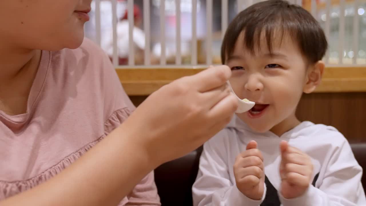 亚洲男孩和他妈妈一起吃面条。视频素材