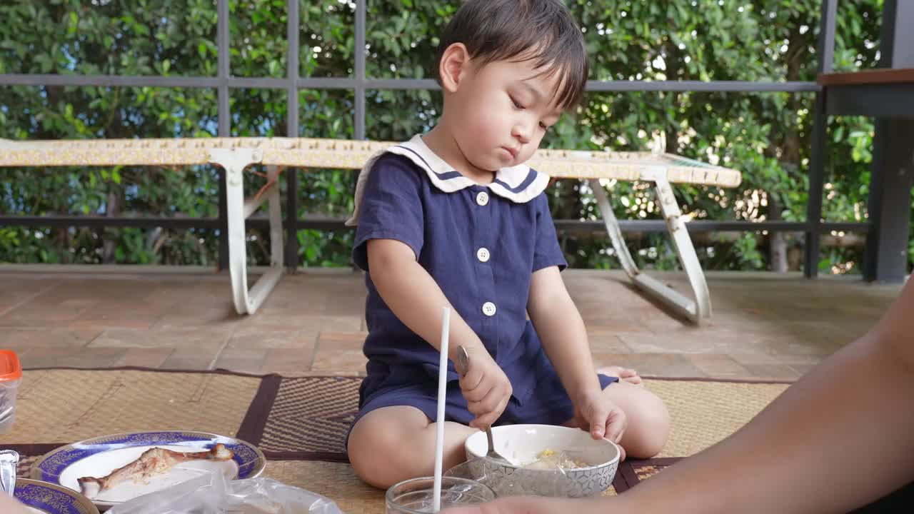 一个男孩和他的妈妈在阳台上愉快地吃午饭。视频下载