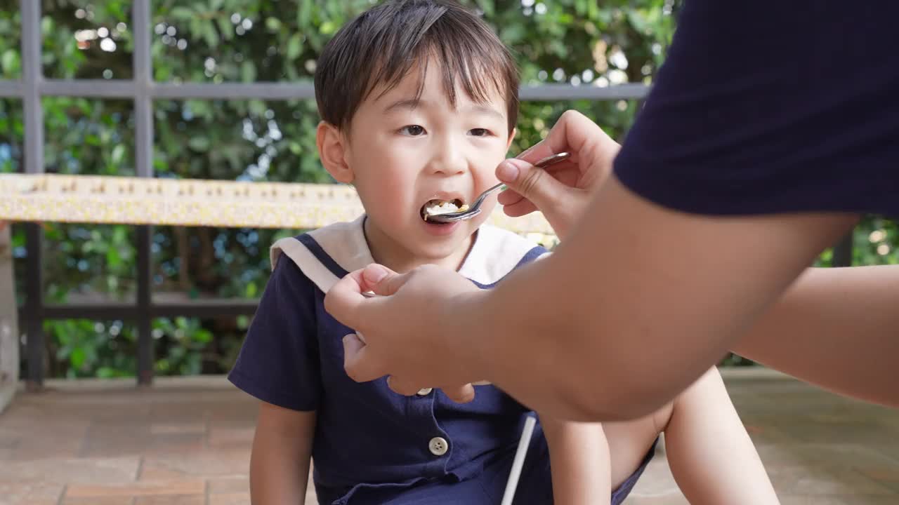 一个男孩和他的妈妈在阳台上愉快地吃午饭。视频下载