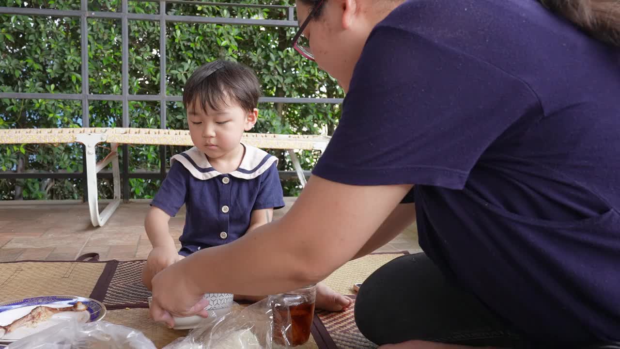 一个男孩和他的妈妈在阳台上愉快地吃午饭。视频下载