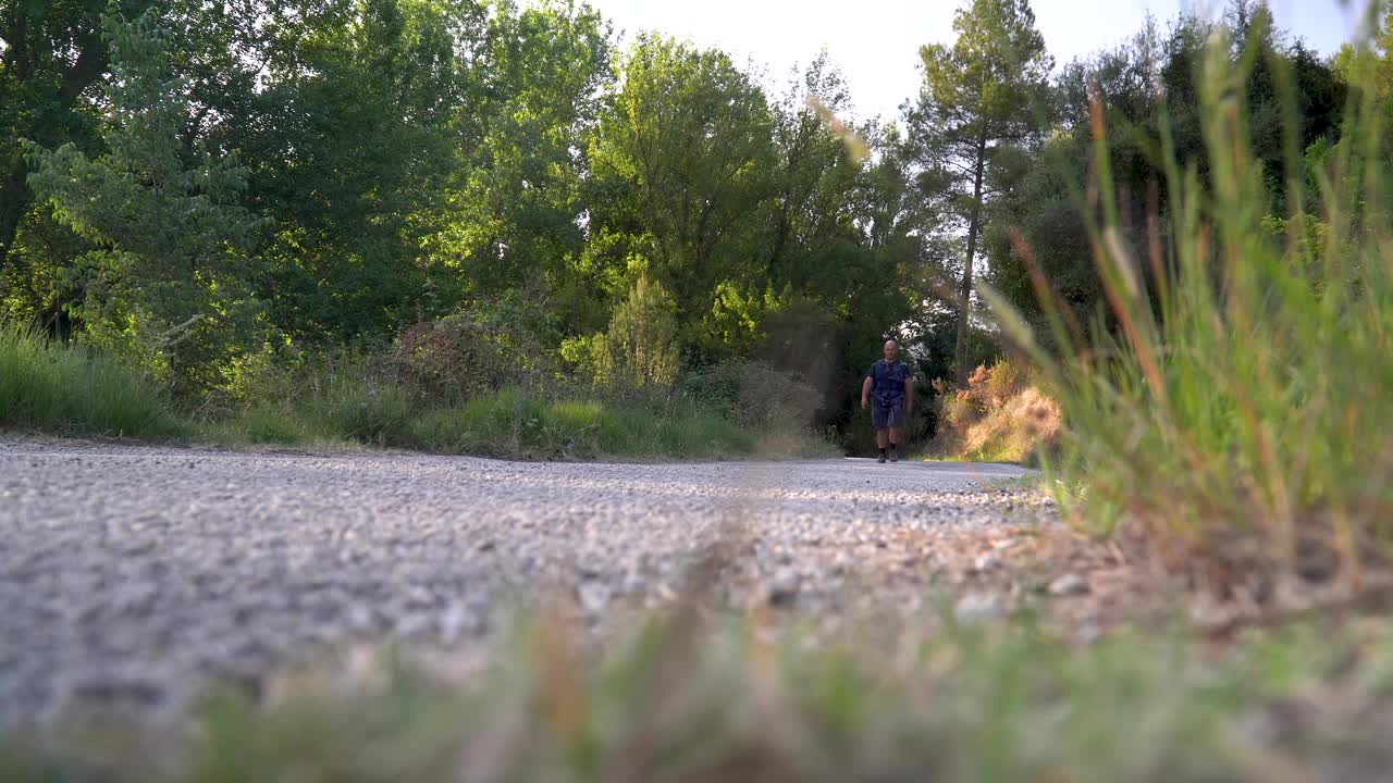 男性徒步旅行者在路上行走，夏日户外，实时视频视频素材