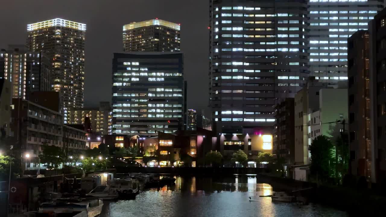 夜景的城市景观与照明摩天大楼反映在平静的河流视频素材