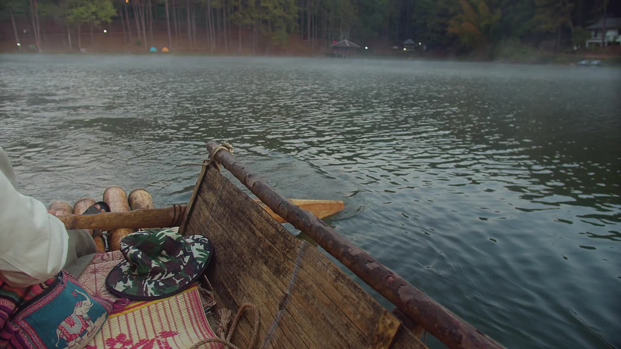 早晨，一个人坐在湖面上划着一只木筏。水面很平静视频素材