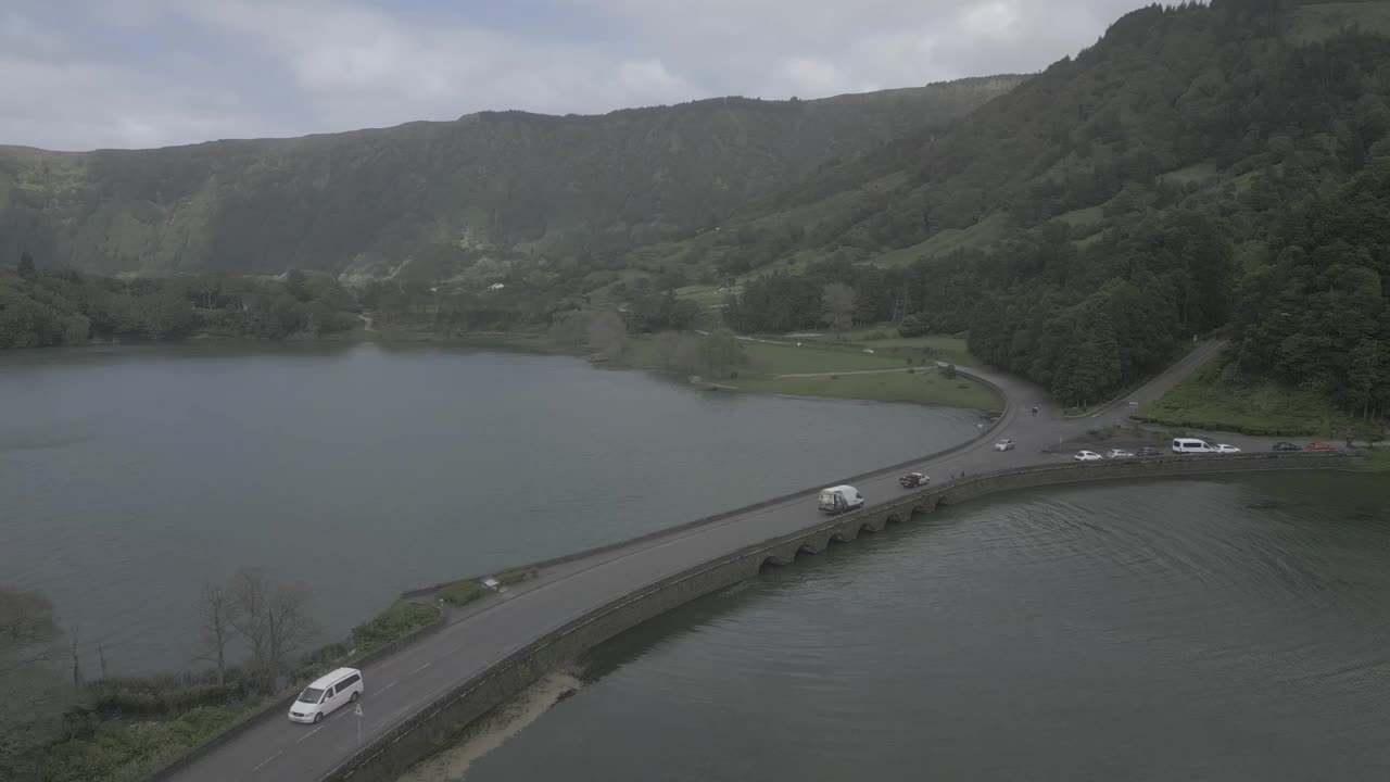 一座桥在宁静的湖面上，四周环绕着郁郁葱葱的青山，鸟瞰图视频素材