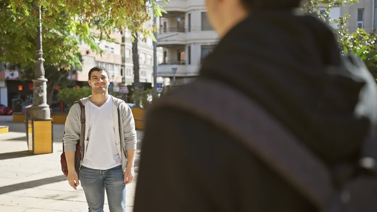 两个男人在城市公园里幸福地拥抱在一起，在阳光下散发着友谊和喜悦。视频素材