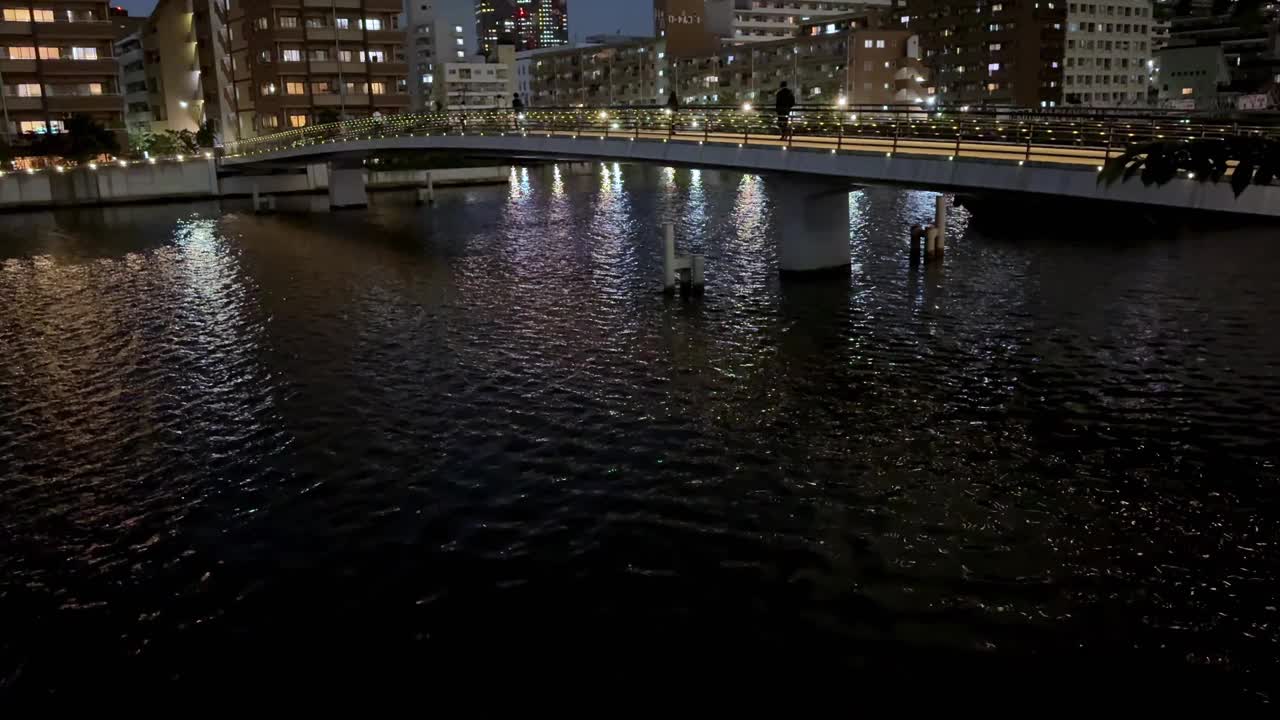 宁静的夜晚城市景观，平静的水面上有一座桥视频素材