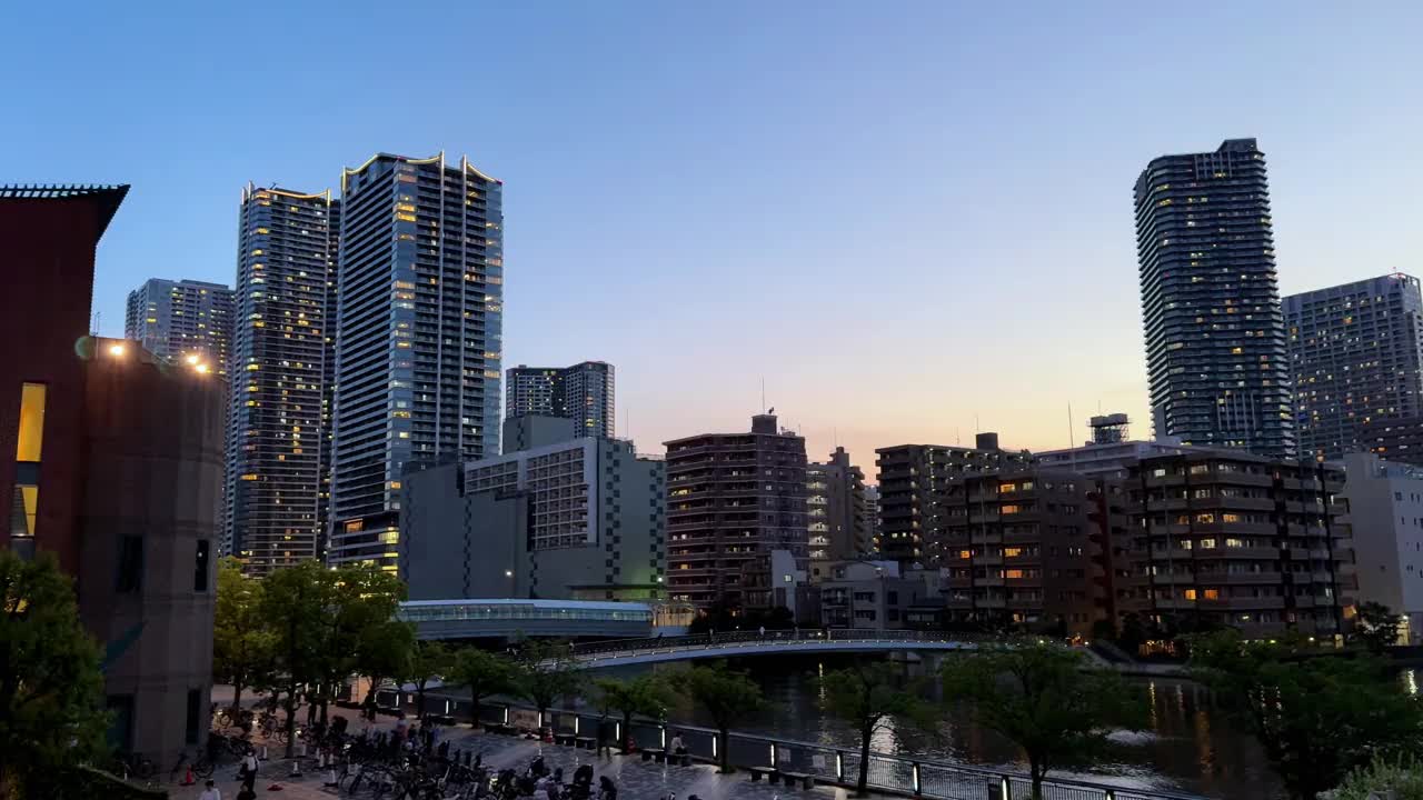 在暮色中，摩天大楼和建筑物映照在河流中的城市景观视频素材