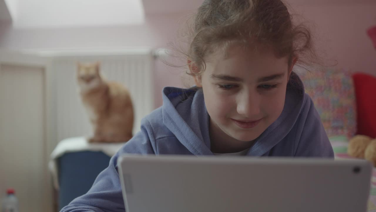 孩子在家用平板电脑上网聊天。女孩在卧室的床上用数码平板电脑看在线视频社交媒体。儿童对社会网络的依赖不健康的生活方式视频素材