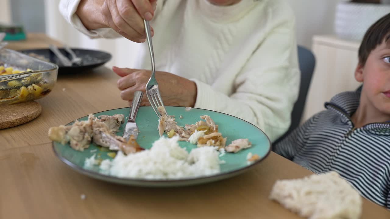 老妇人用勺子喂小男孩，餐桌上养育和关怀的时刻，代际关系，家庭爱，祖父母和孙子在一起视频素材